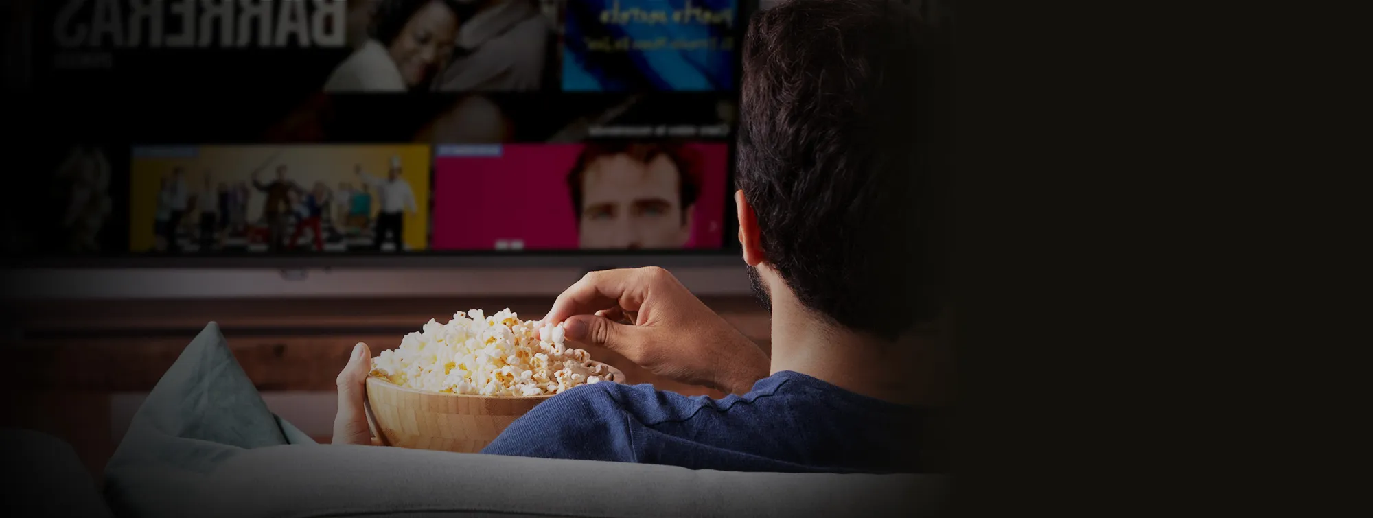 Hombre sentado en sala de casa viendo películas streaming con plan Claro